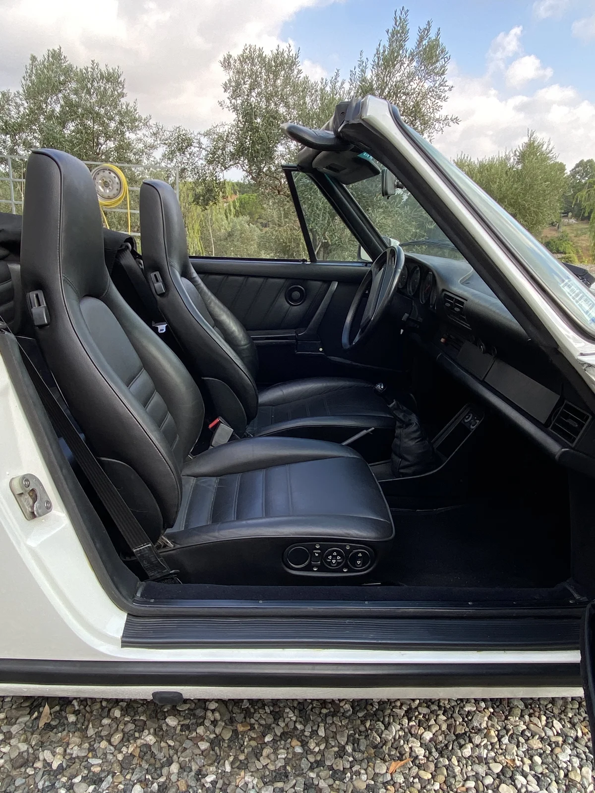 Front seats of a white Porsche 911 in black leather, seen from outside with the door open