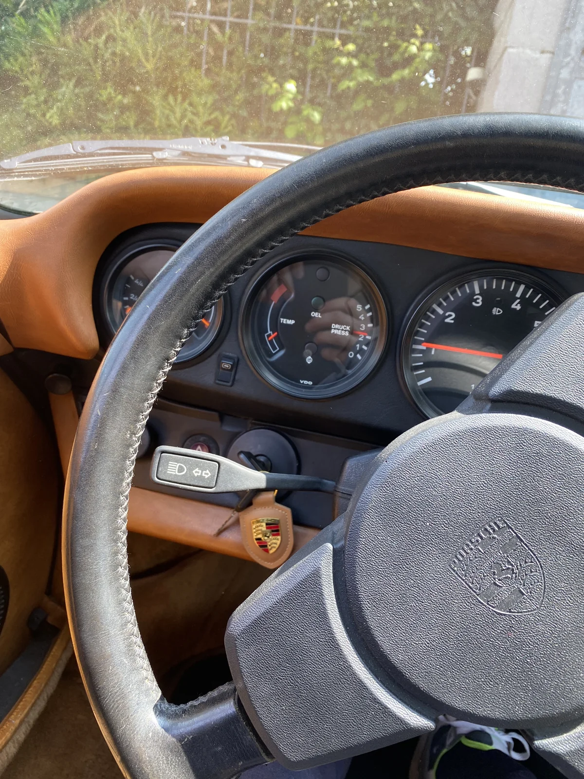 Porsche 911 steering wheel trimmed in tan leather with restored dashboard and instruments