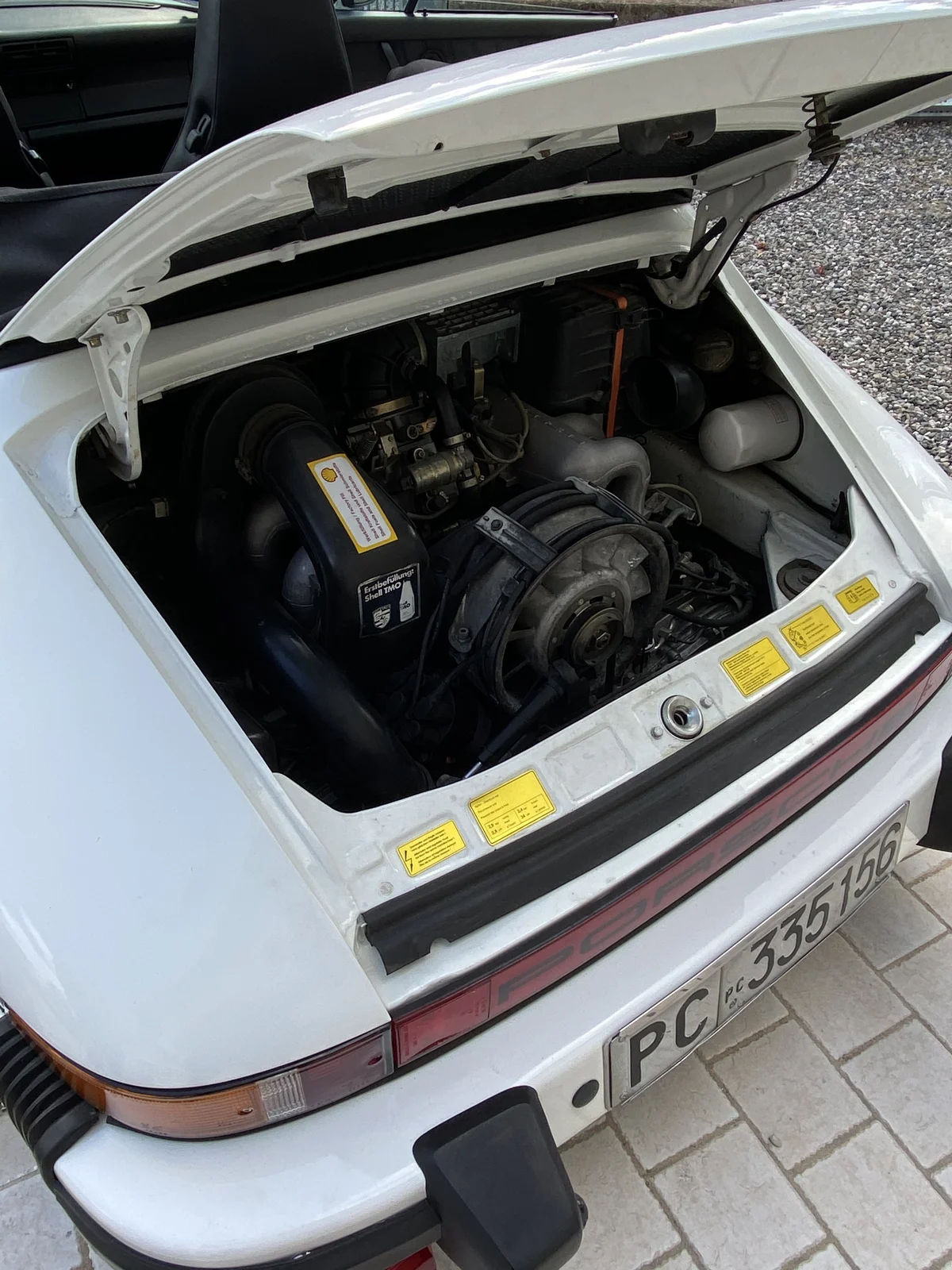 White Porsche 911 with rear bonnet open and engine visible