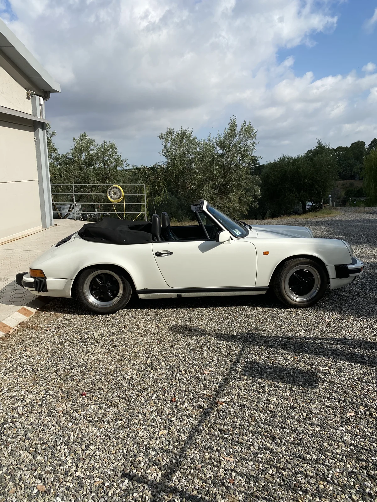 White Porsche 911 SC Cabriolet with soft top down, left profile