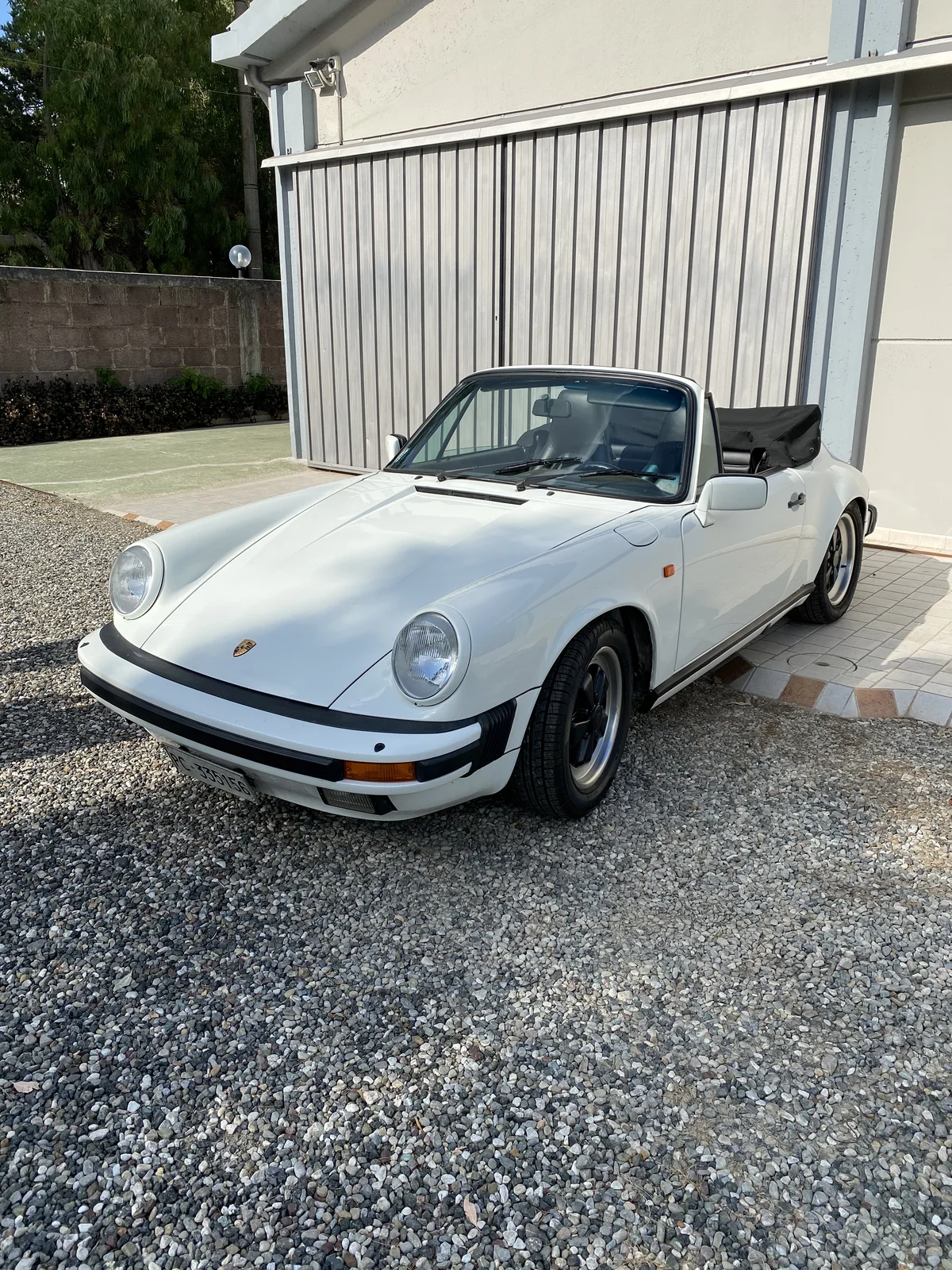 Restored white Porsche 911 SC Cabriolet, three-quarter front view on gravel
