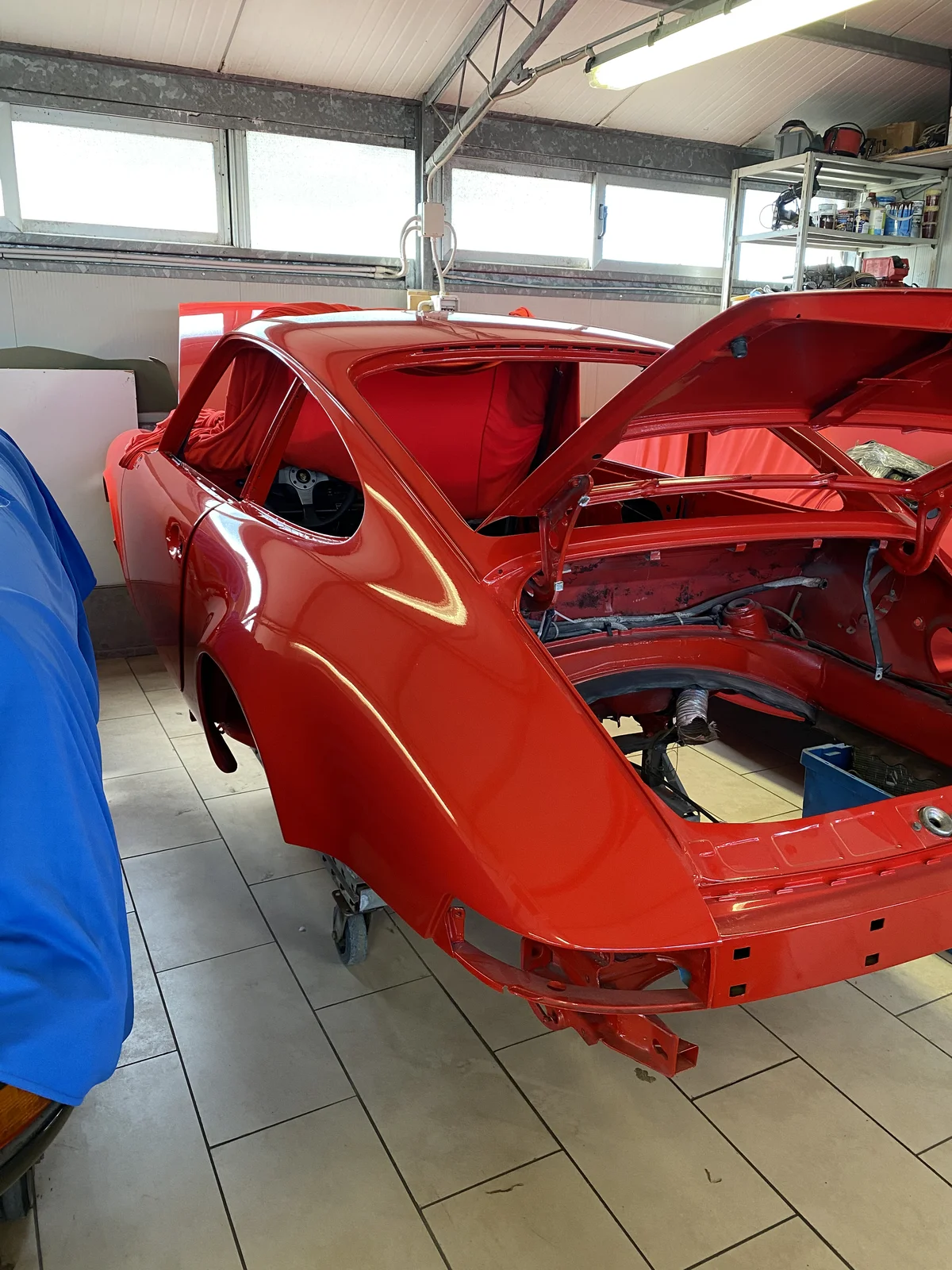 Bare red Porsche 911 shell in the workshop during full bodywork restoration