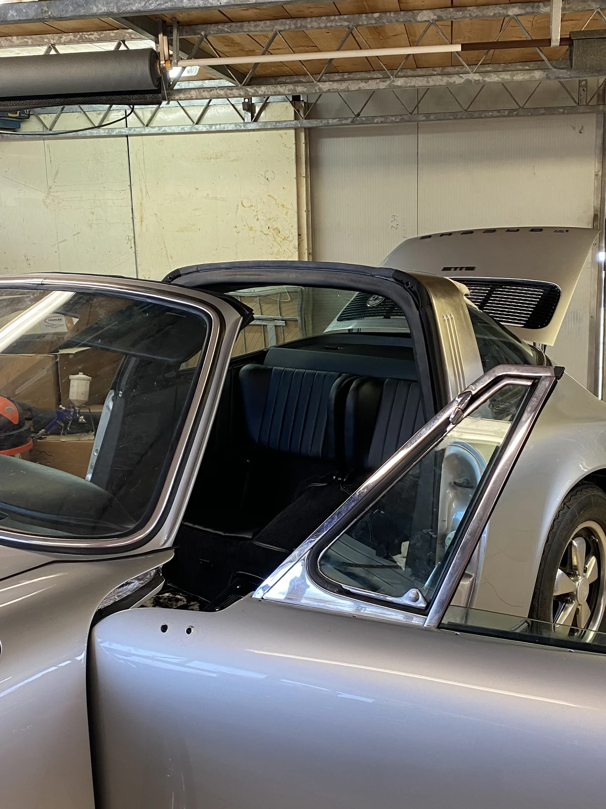 Silver Porsche 911 Targa with door open inside the workshop