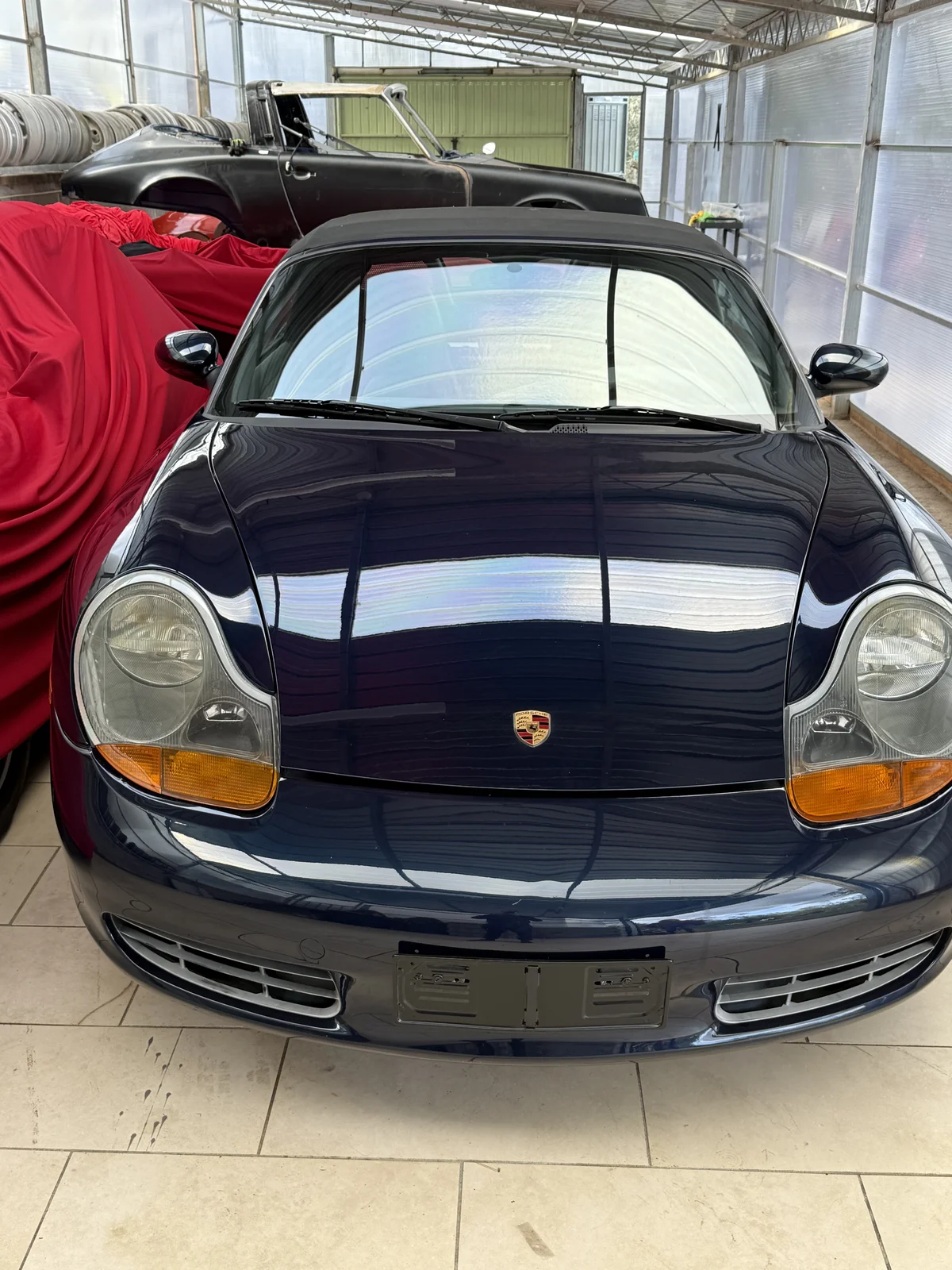 Blue Porsche Boxster front view at the workshop entrance