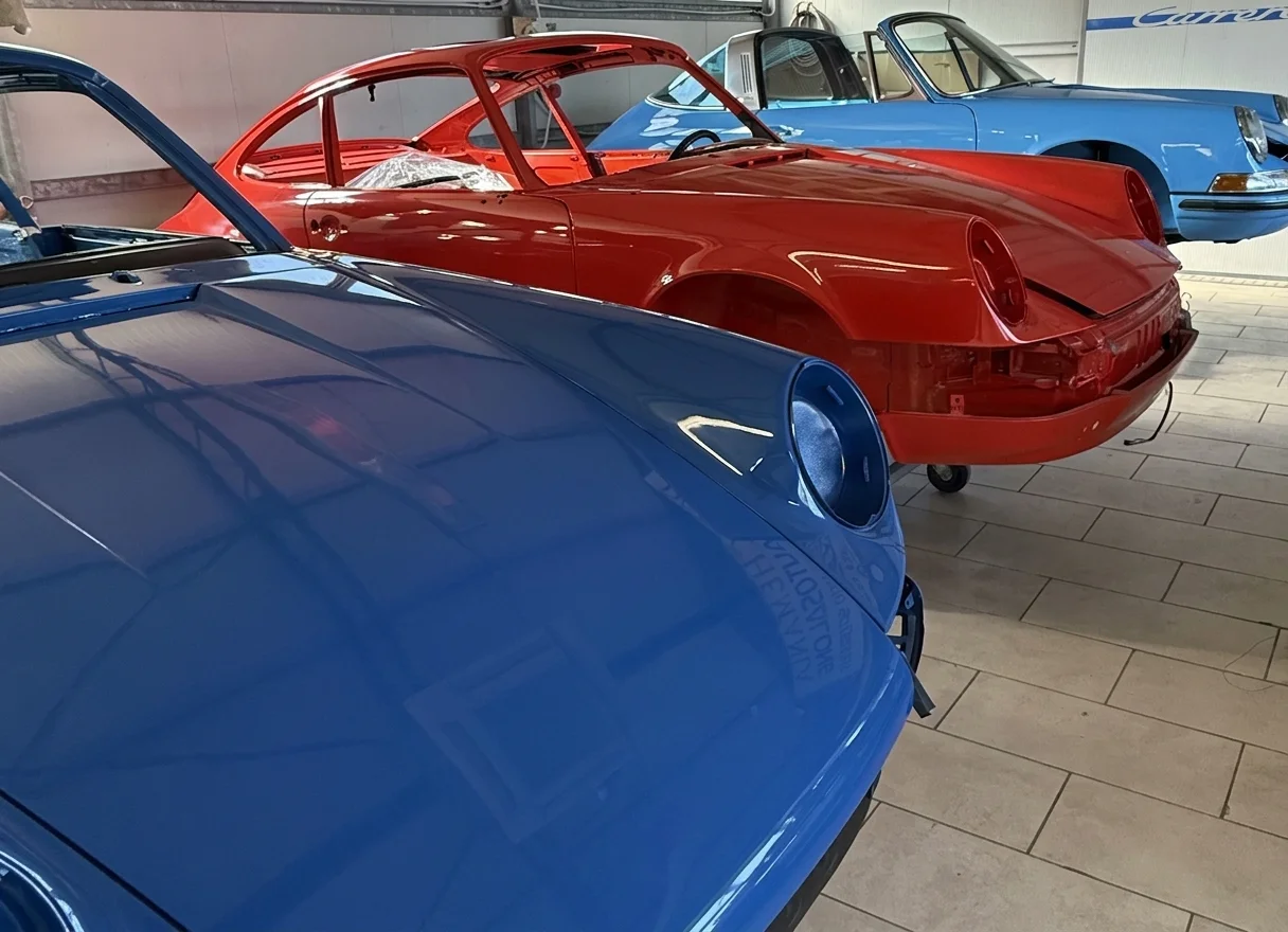 Two classic Porsche 911s in the showroom, one red and one blue